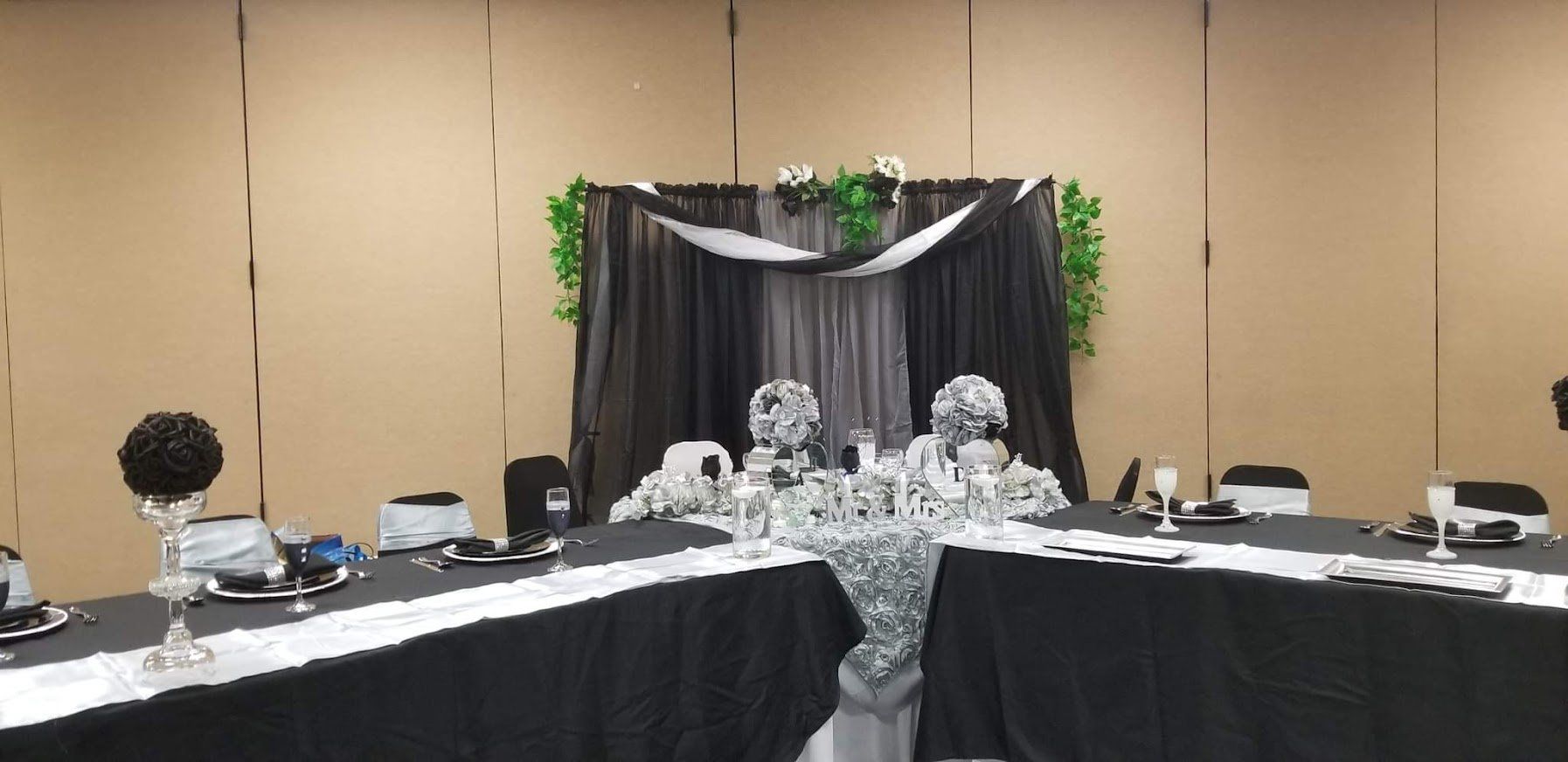 Decorated banquet table with black-and-white drapes and silver centerpieces in a conference room