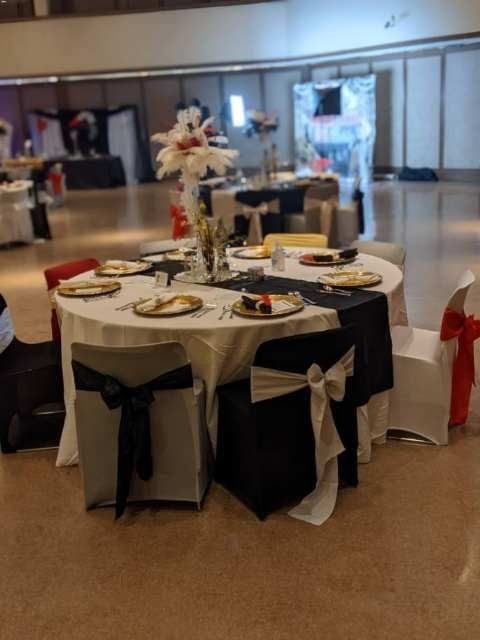 Round banquet table set with plates and floral centerpiece in a decorated event hall.