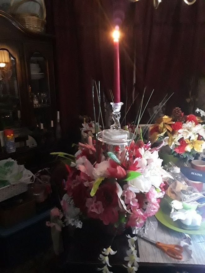 Floral altar with a lit pink candle, arranged on a table in a dim room