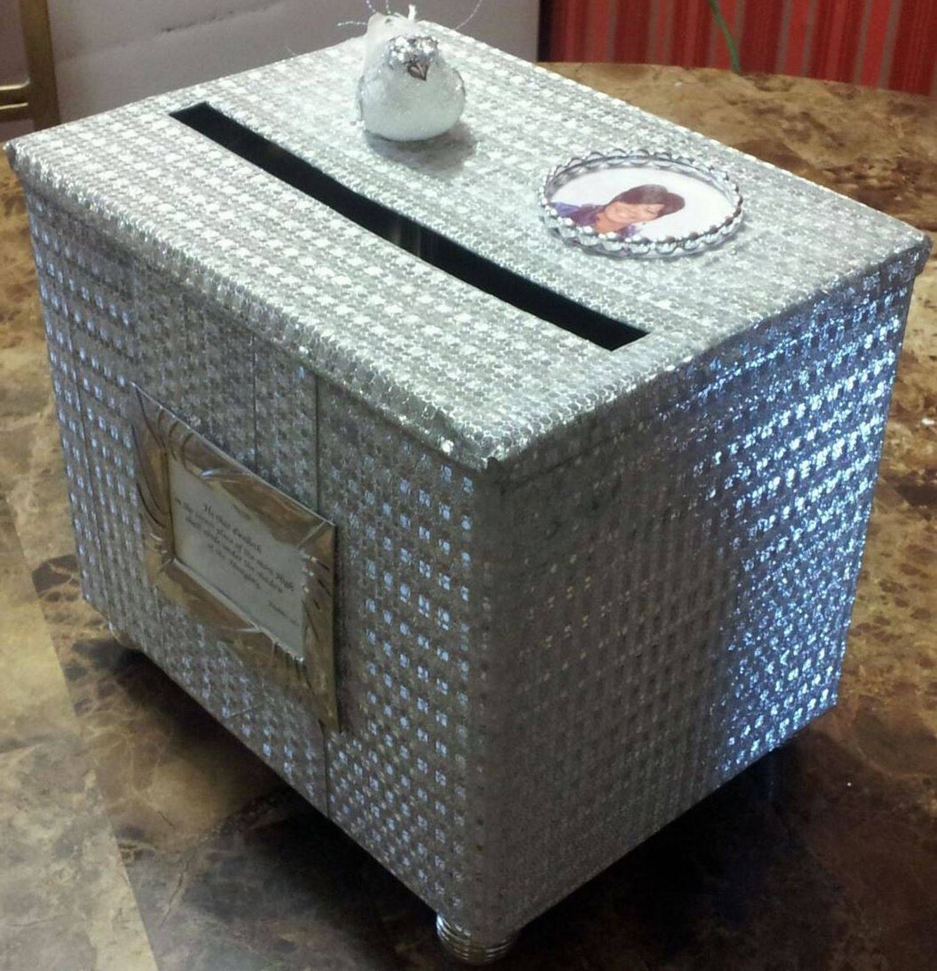 Bubble-wrapped white ballot box with slot and labels, sitting on a table.