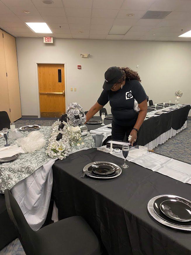 Woman arranging a black-and-white banquet table centerpiece in a banquet hall room