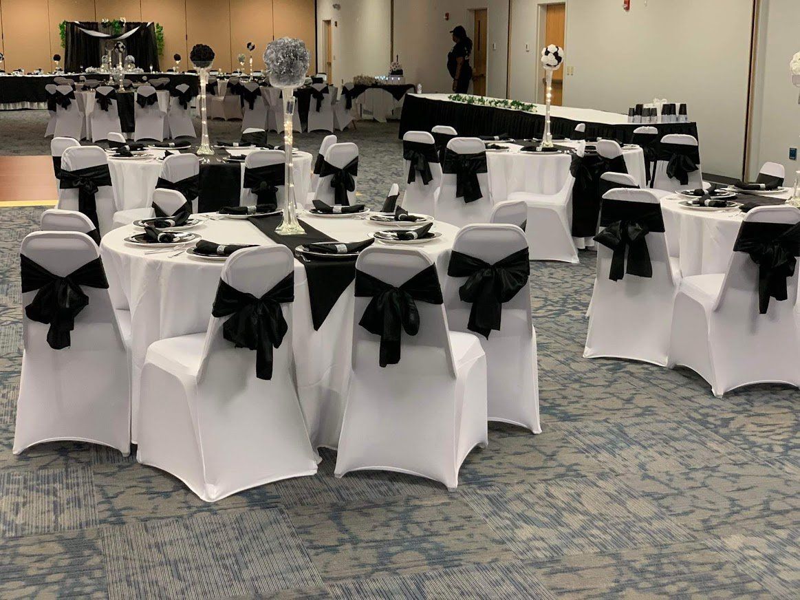 Banquet hall with round tables and chairs dressed in white and black table linens