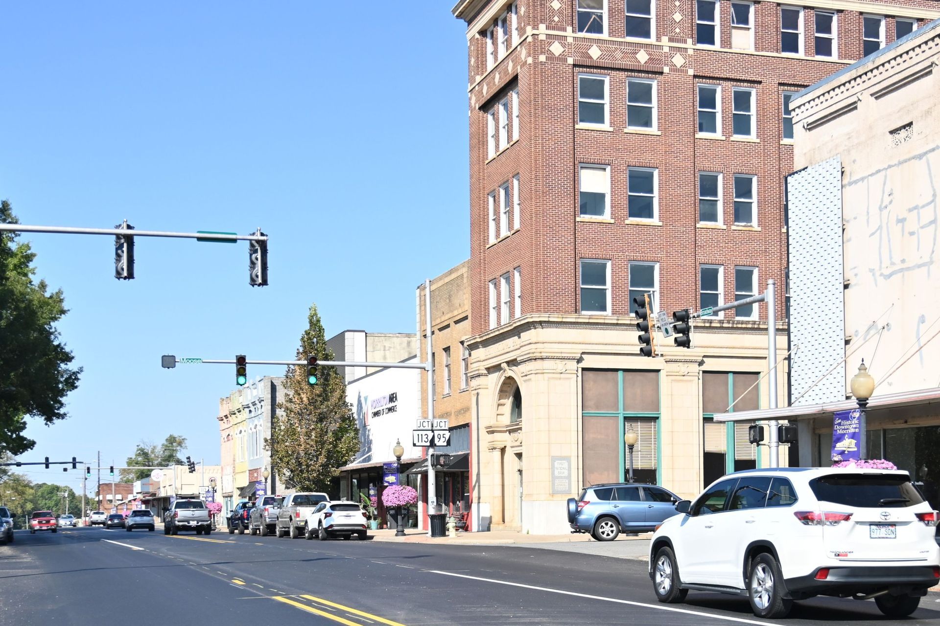 Downtown street with cars, traffic lights, and a brick building on a sunny day in modern day conway county arkansas