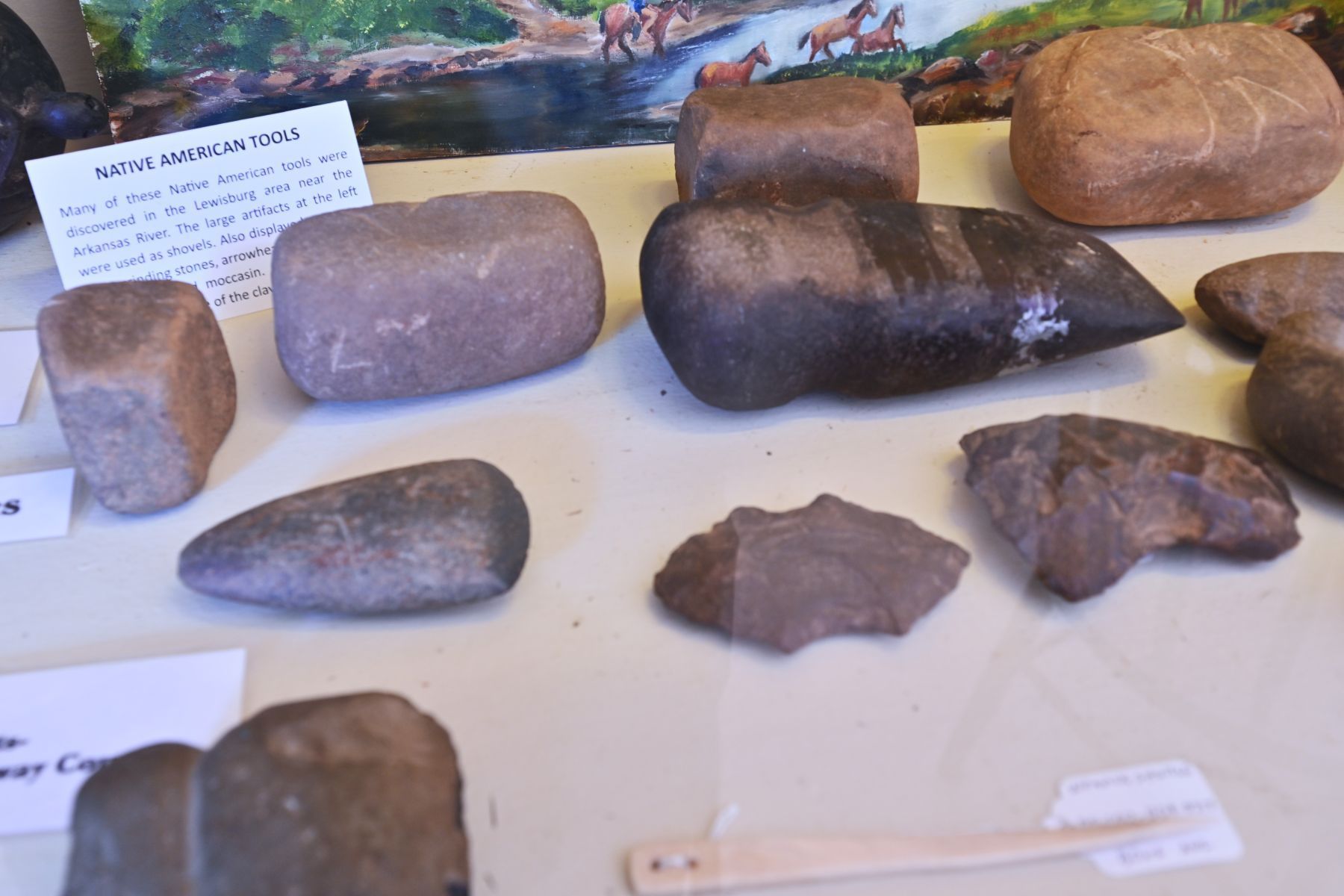 Display of assorted stone tools and artifacts on a museum exhibit table displayed in conway county