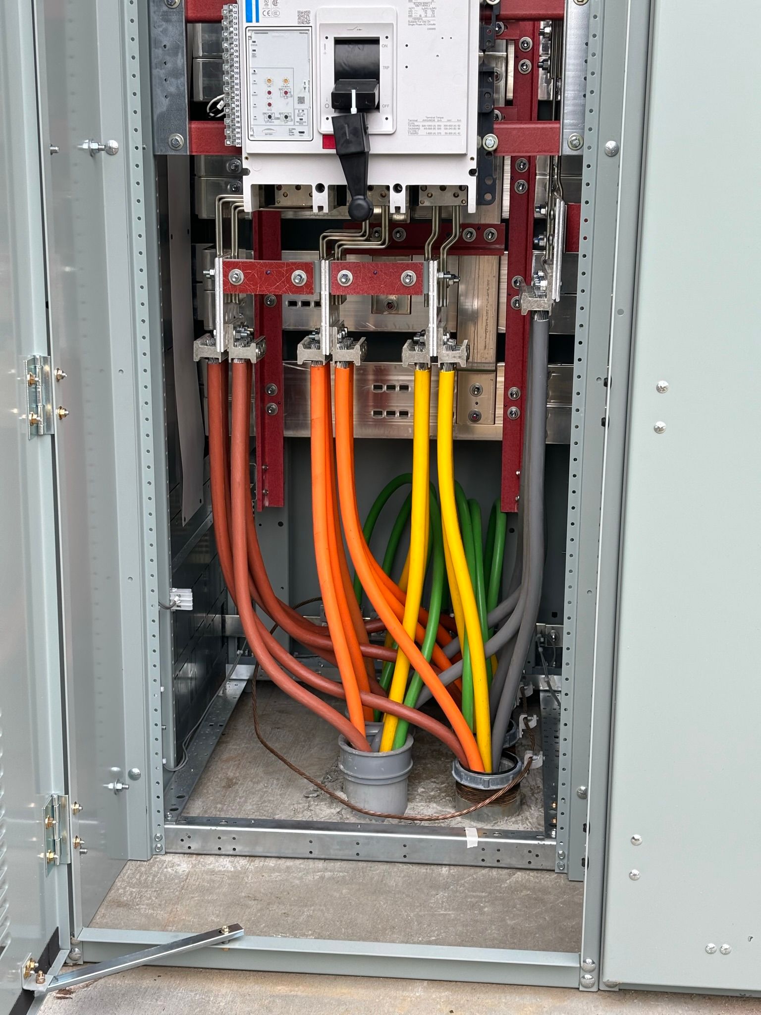 Electrical panel with colored cables connected to a circuit breaker inside a metal enclosure.