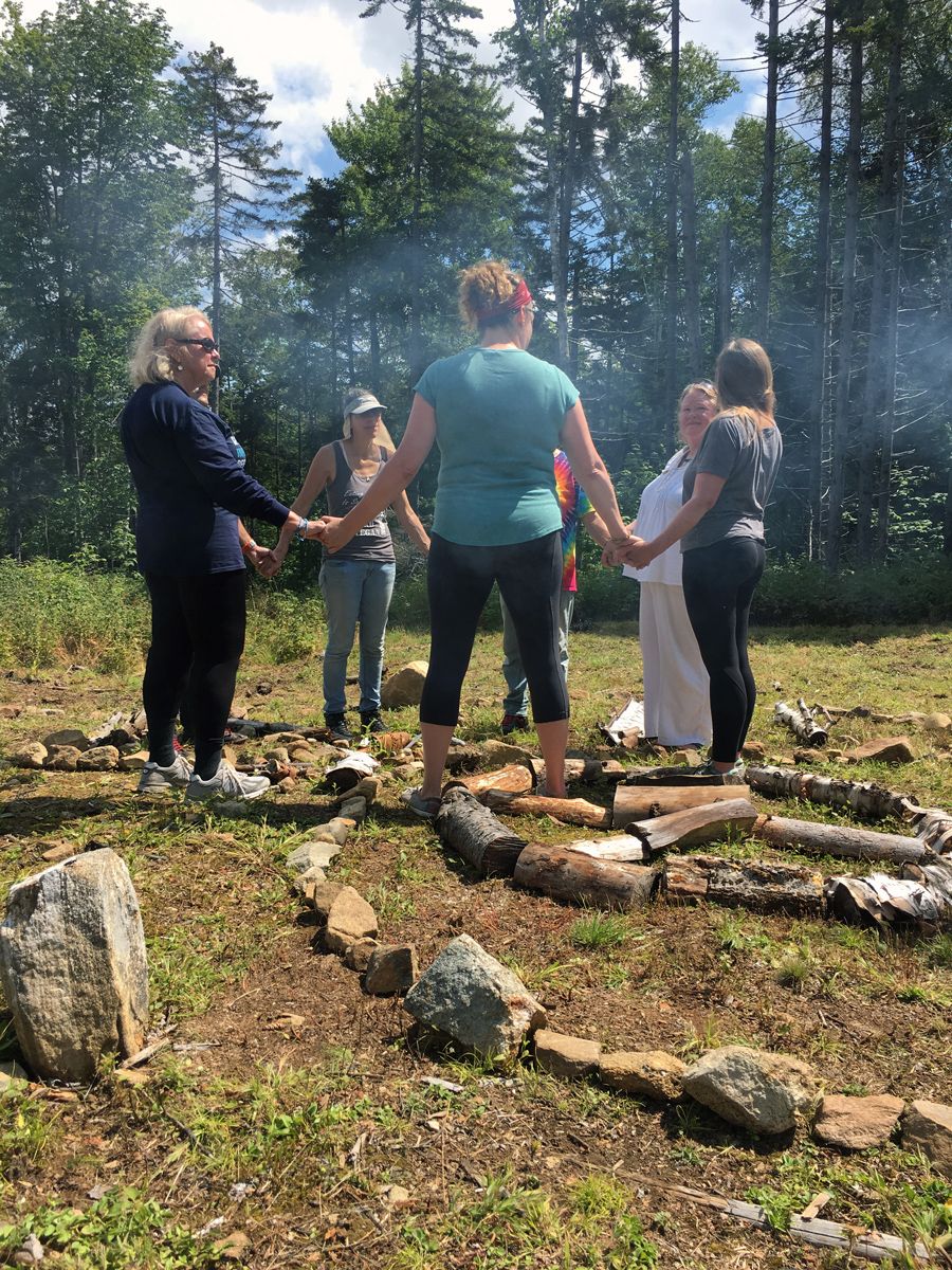 Group holding hands and standing around a campfire
