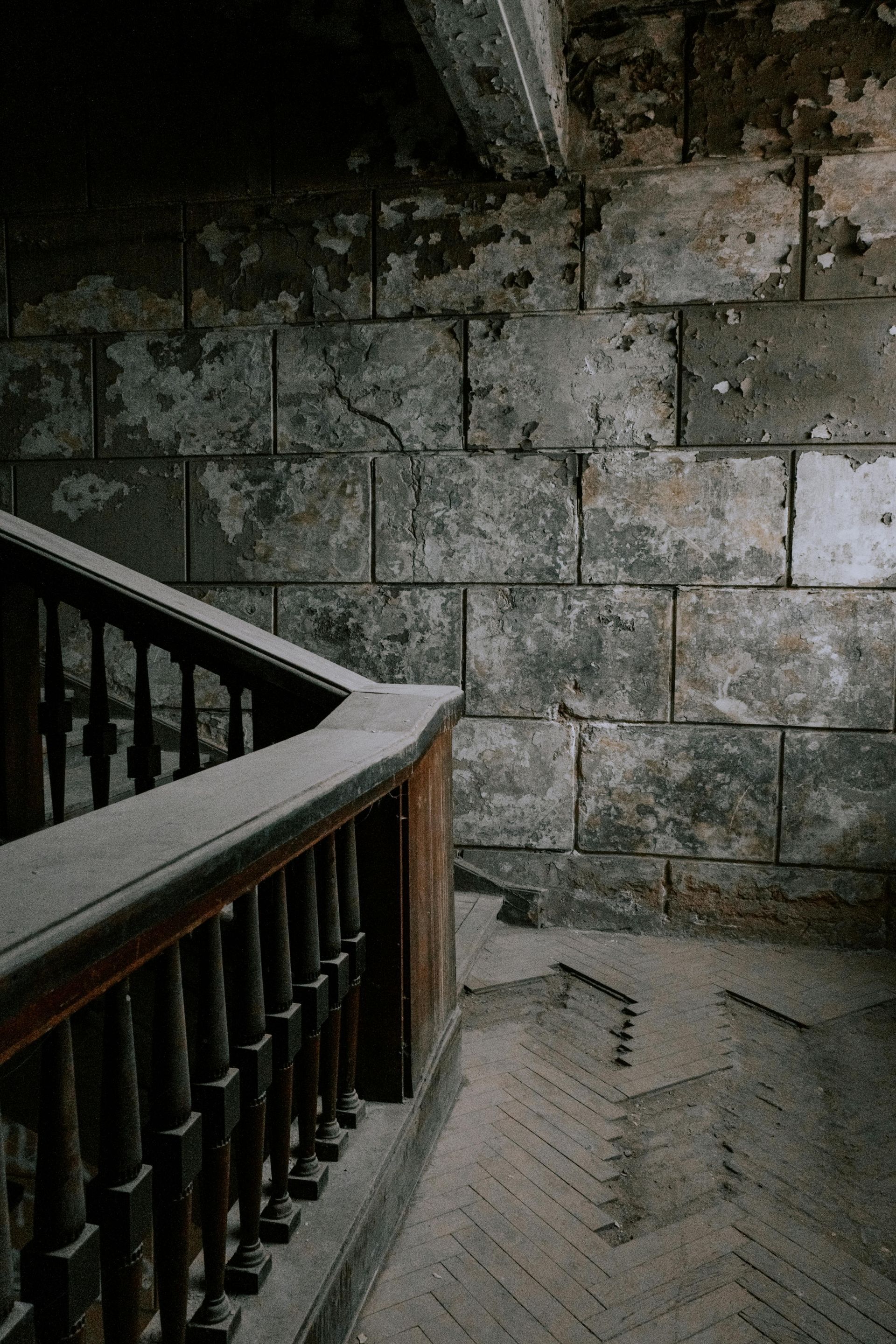 A staircase with a wooden railing and a brick wall.