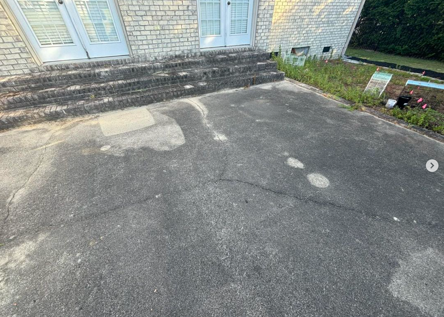 A brick house with a concrete driveway in front of it.