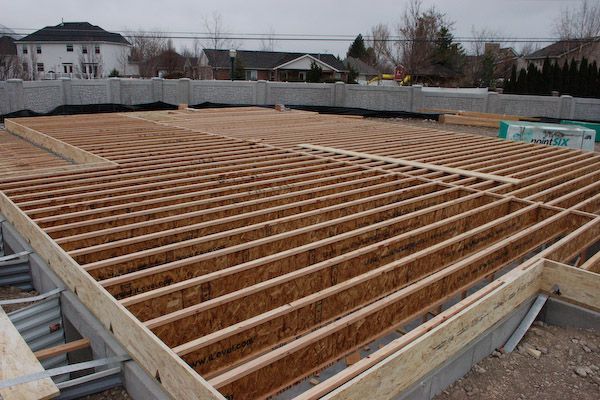 Wooden floor joists laid across a concrete foundation; construction site.