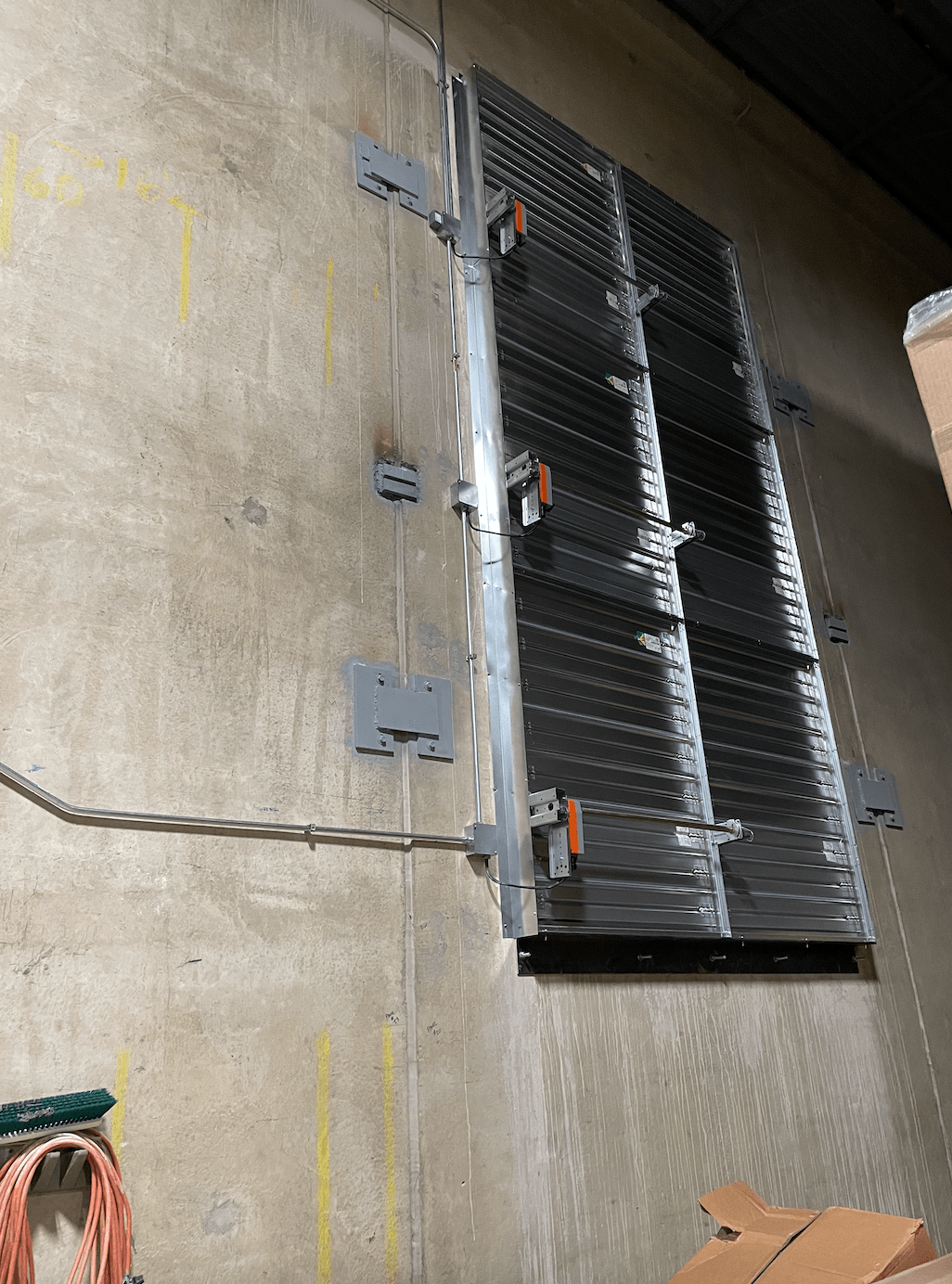 A large metal fence is attached to a concrete wall.