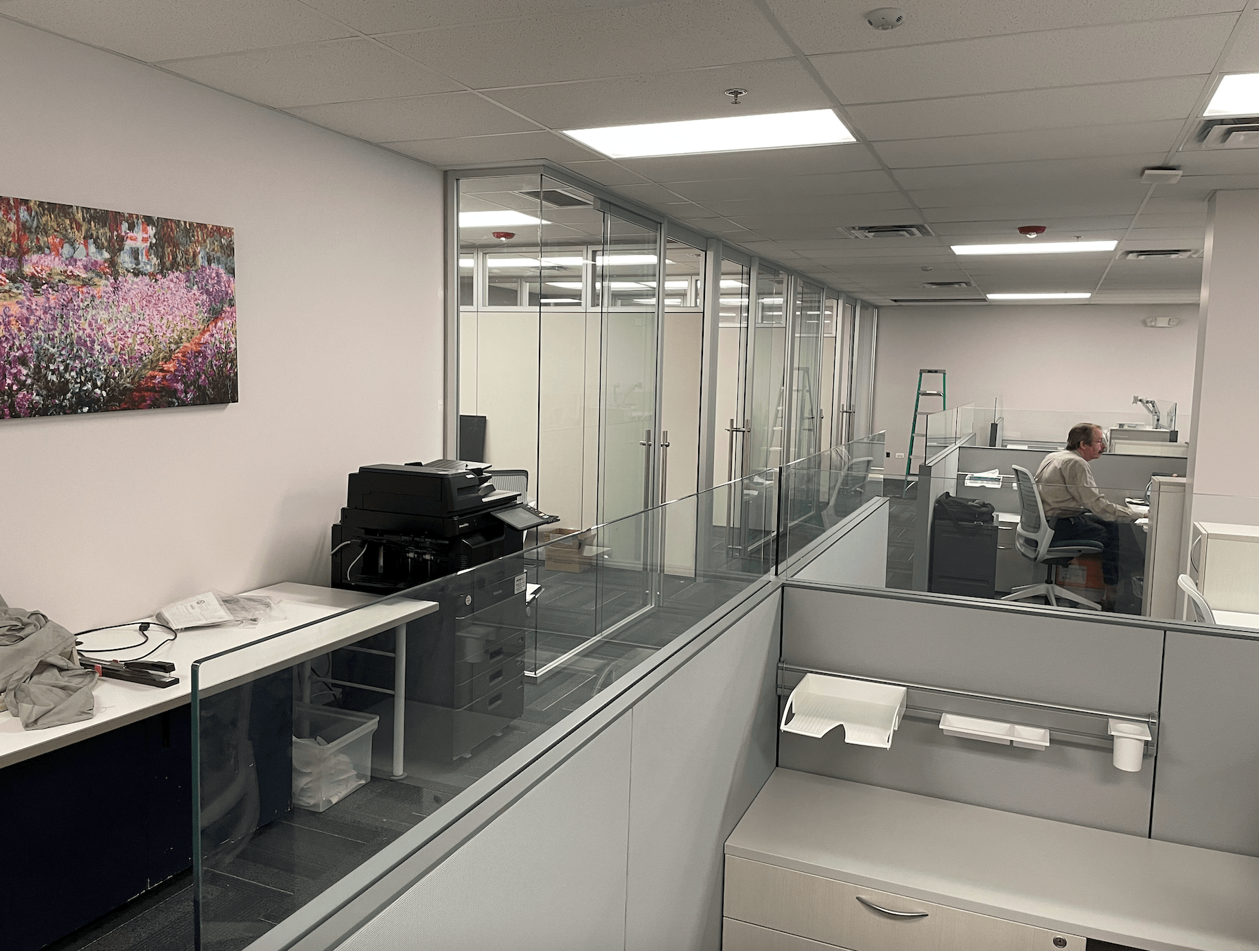 A man is sitting at a desk in a cubicle in an office.