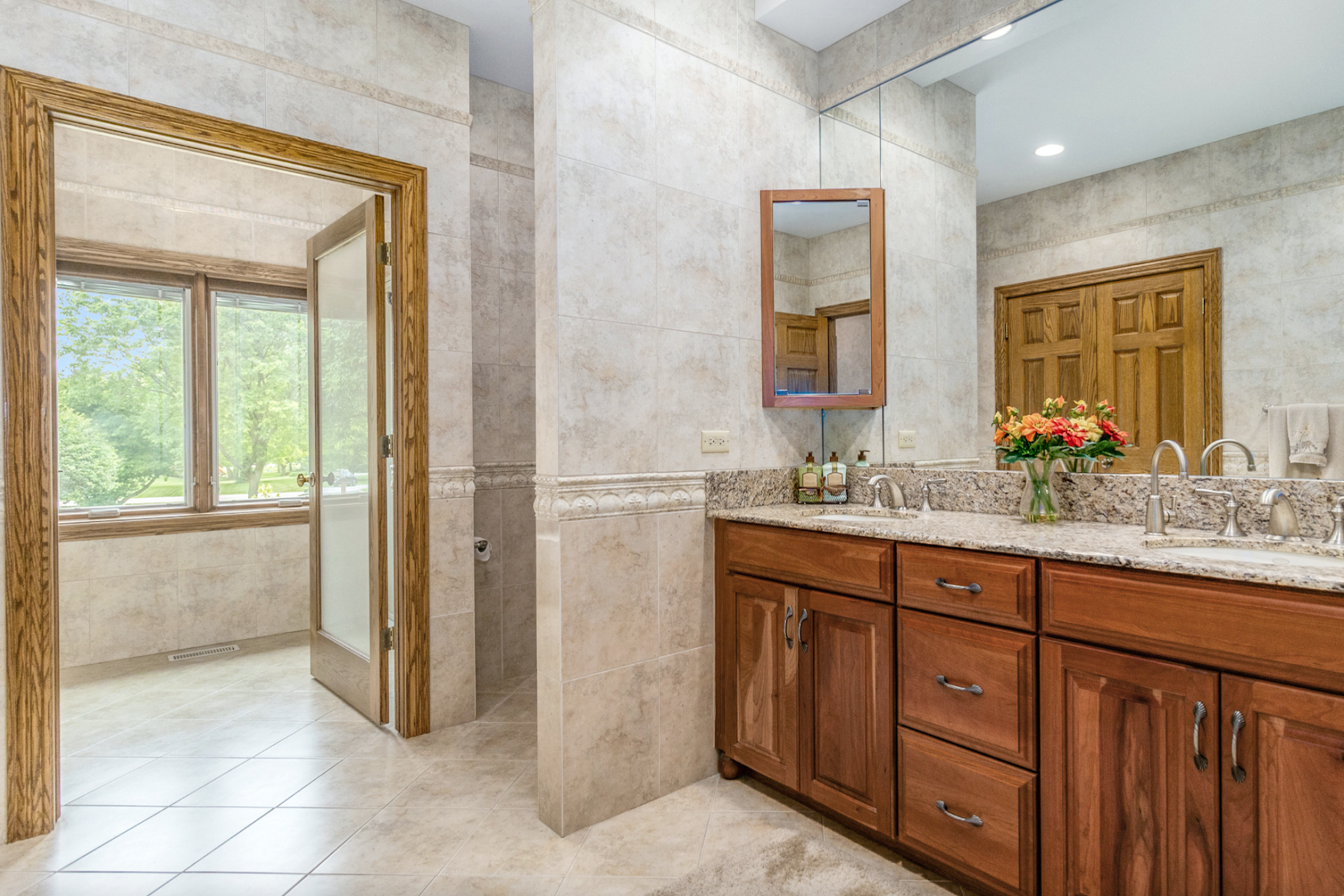 A bathroom with two sinks , a mirror , and wooden cabinets.