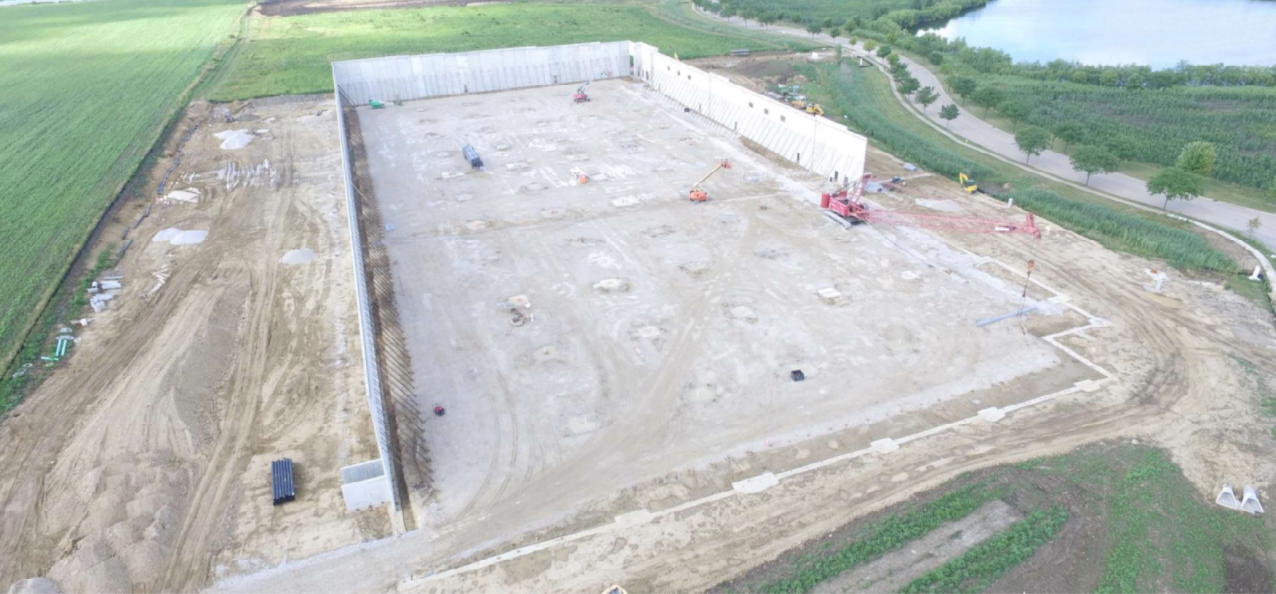 An aerial view of a large building under construction in the middle of a field.