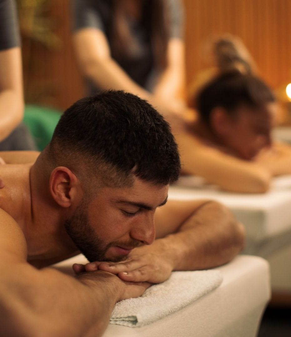 Person resting face-down on a towel at a spa, with others blurred in the background.