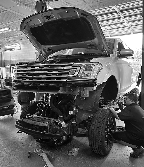 A black and white photo of a man working on a truck in a garage. | Pearland Automotive