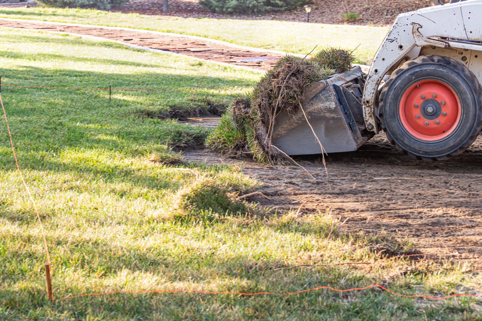 A tractor removing sod on a commercial property
