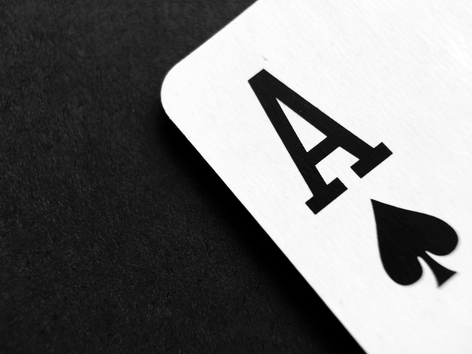 Ace of spades playing card on a black surface.