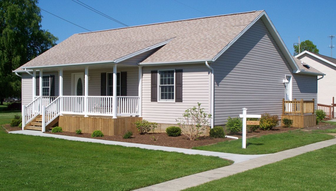 A small house with a porch and a sign in front of it