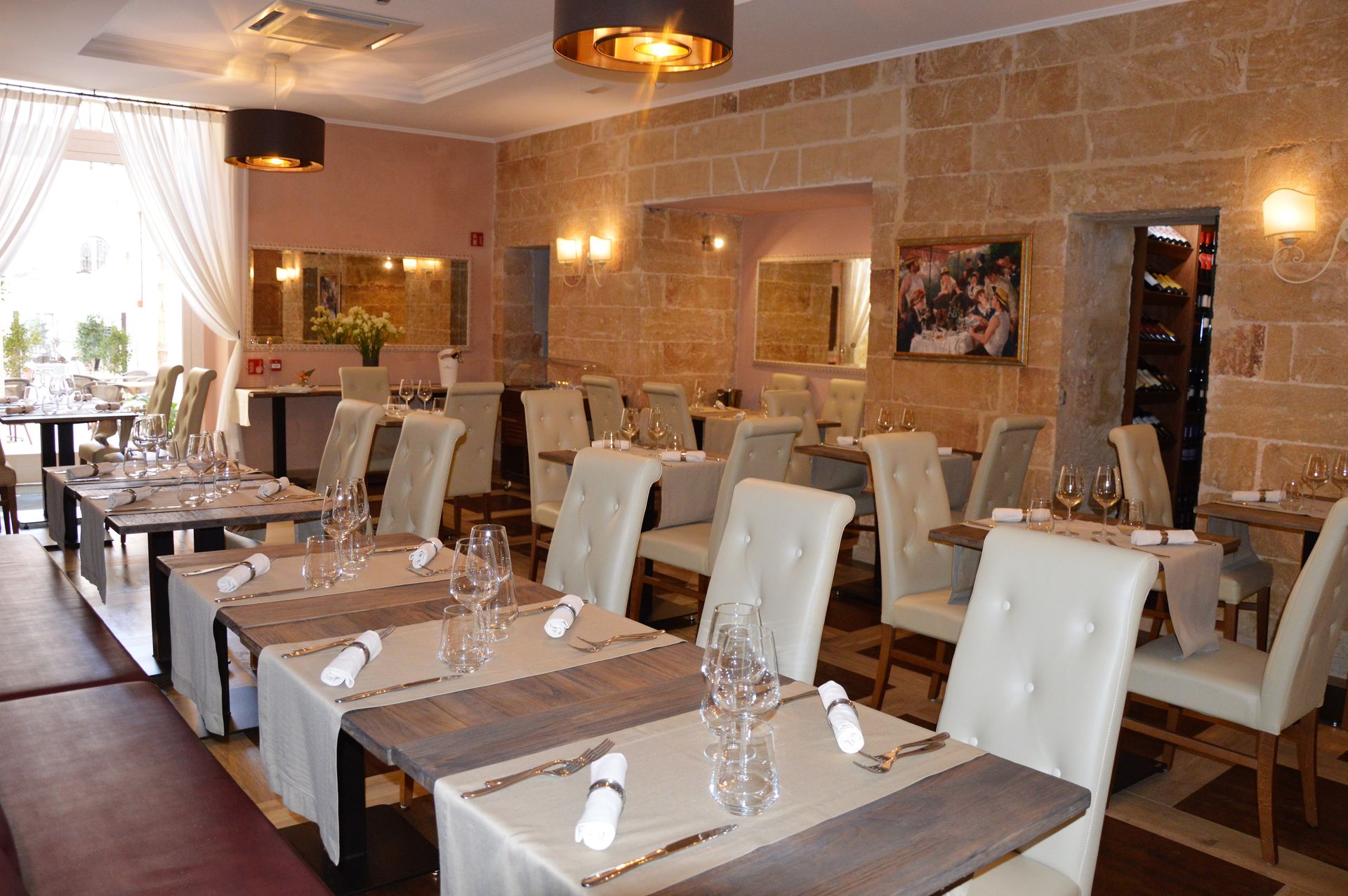 Restaurant interior: Creamy walls, tables set with white linens, upholstered chairs, and a marble floor.