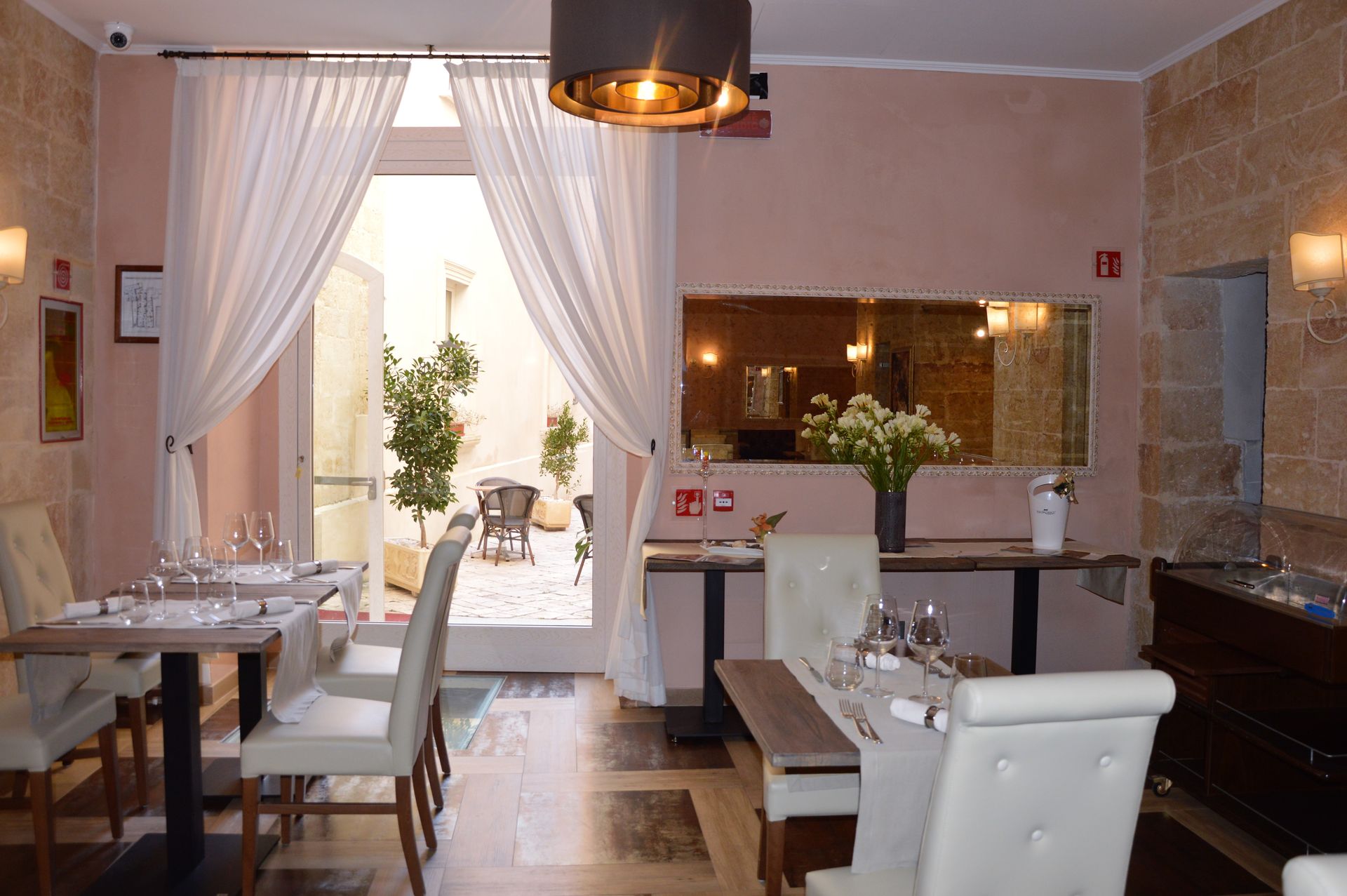 Restaurant interior: tables set for dining, doorway to an outdoor patio, soft lighting.
