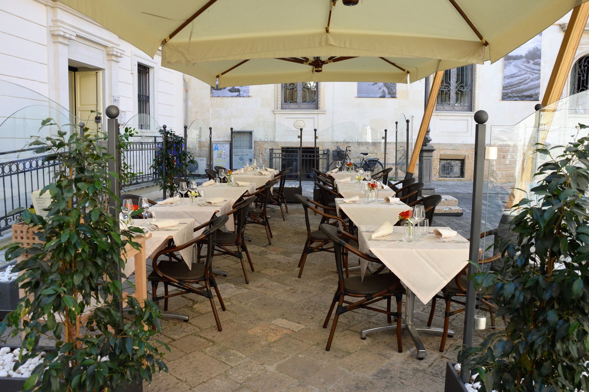 Outdoor restaurant seating with tables and chairs under umbrellas.