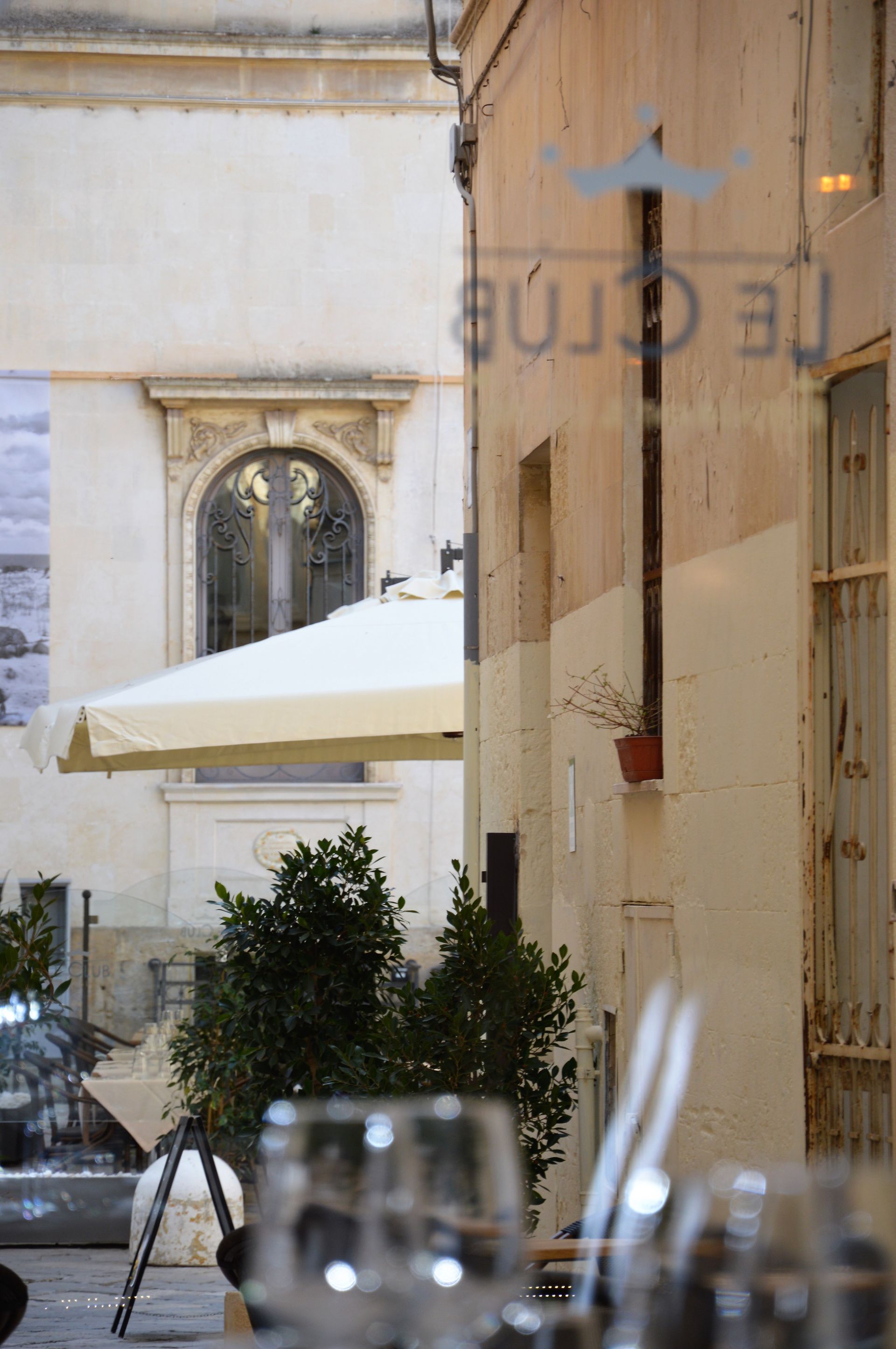 Restaurant patio with tables, plants, and a sign that reads 