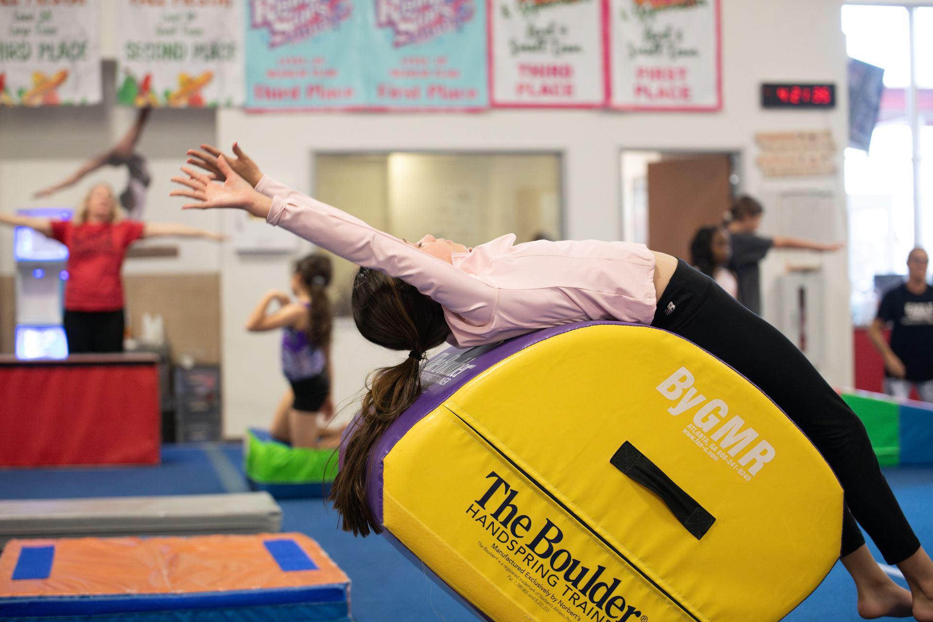 A female gymnast is doing a trick on a trampoline.