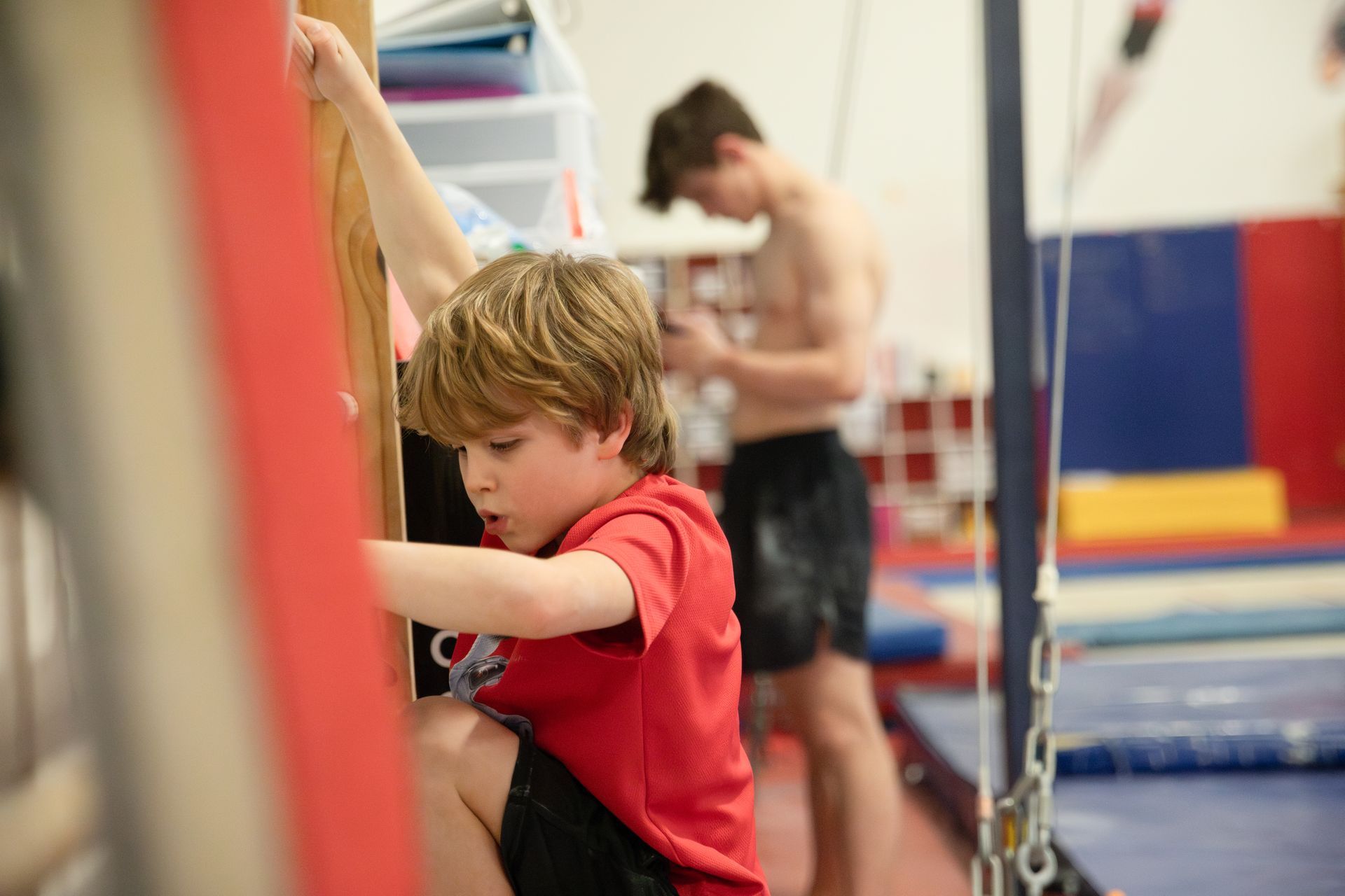 A young boy is doing a handstand on a trampoline.