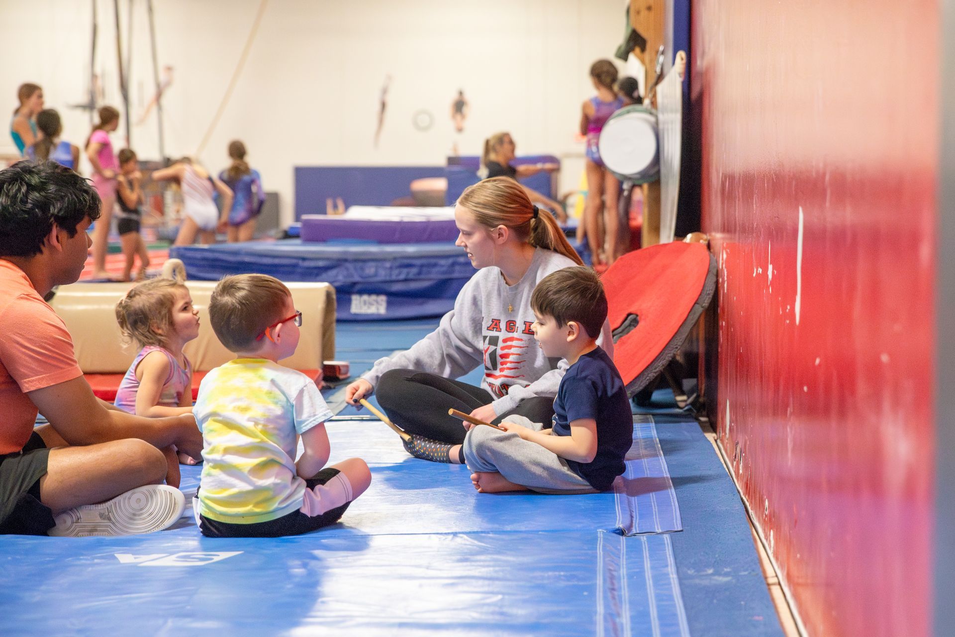 A woman is helping a little girl climb a bar in a gym.