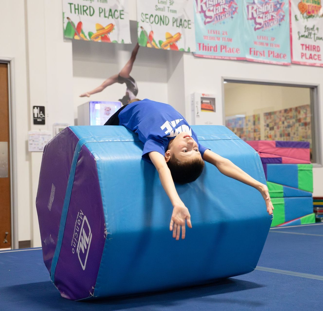 A female gymnast is doing a flip on a trampoline.