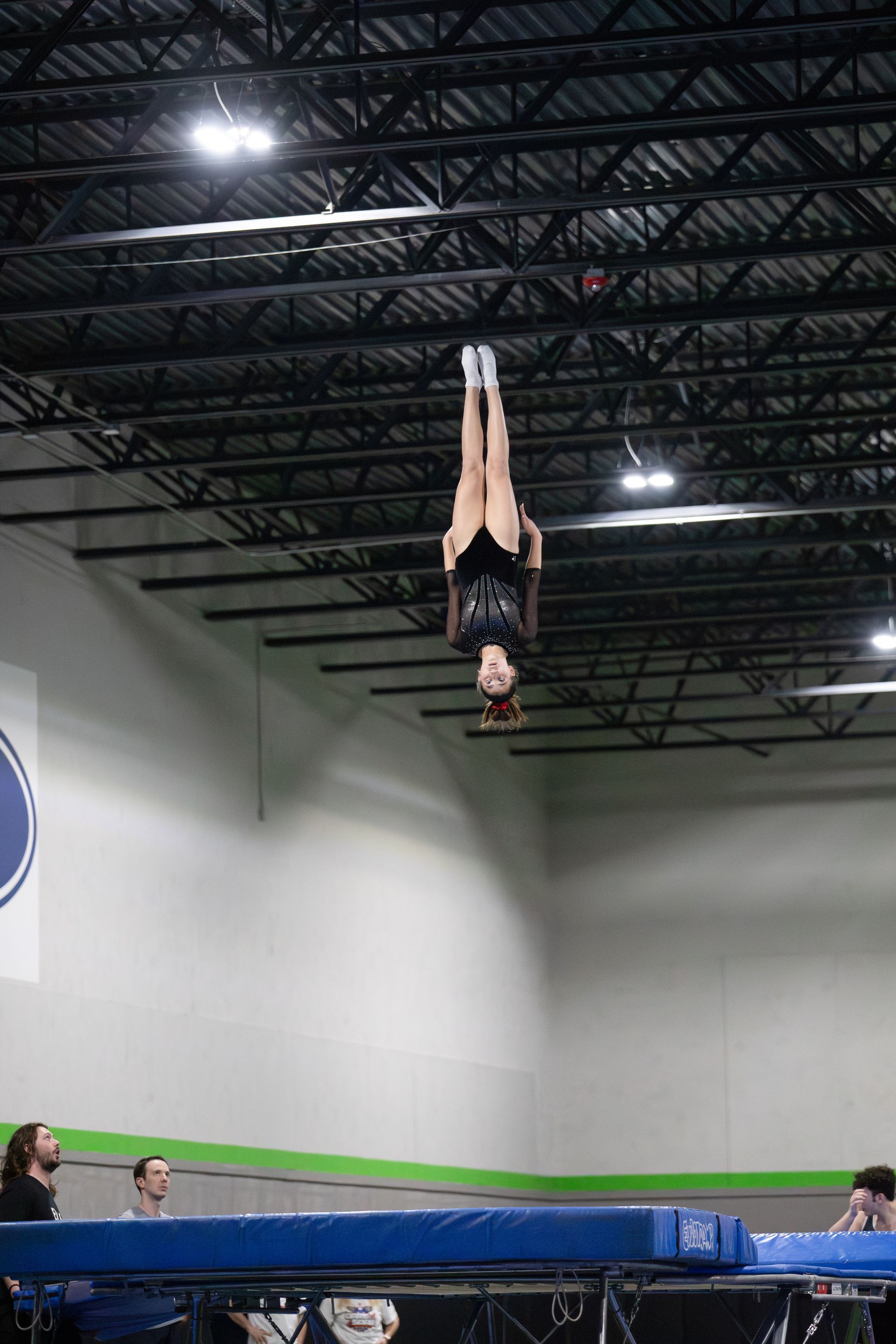 A woman is doing a handstand on a trampoline in a gym.