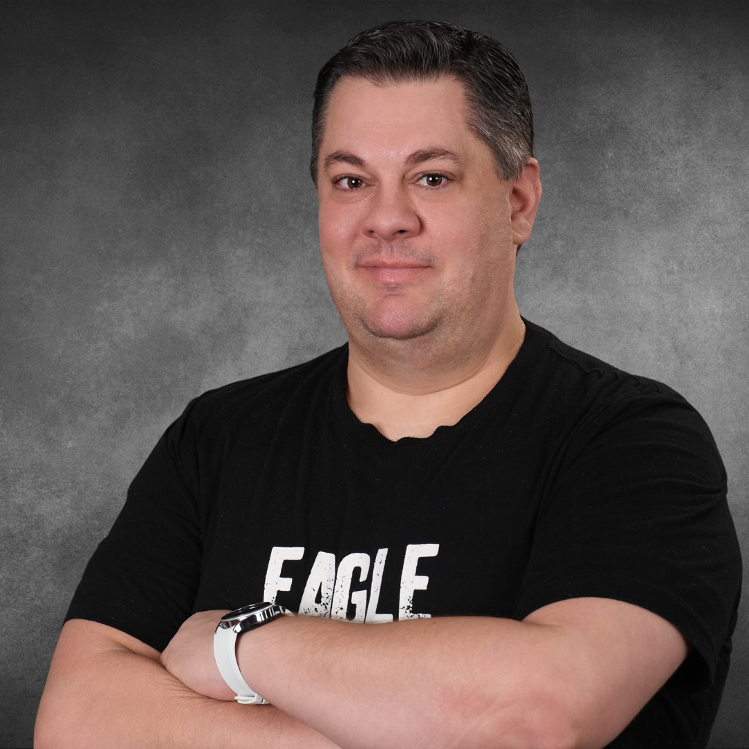 A man wearing a black eagle shirt with his arms crossed