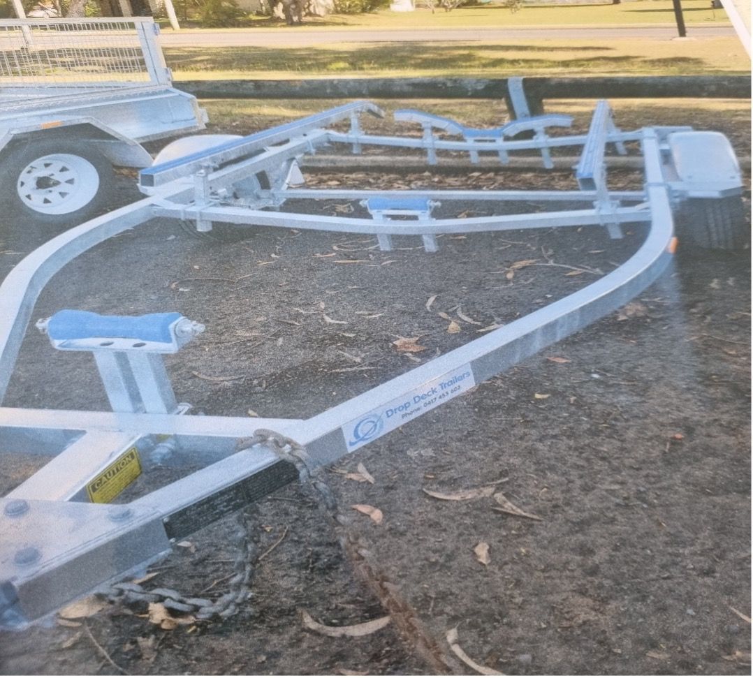 A Boat Trailer is Parked in The Dirt Next to a Truck — Drop Deck Trailers In Urangan QLD