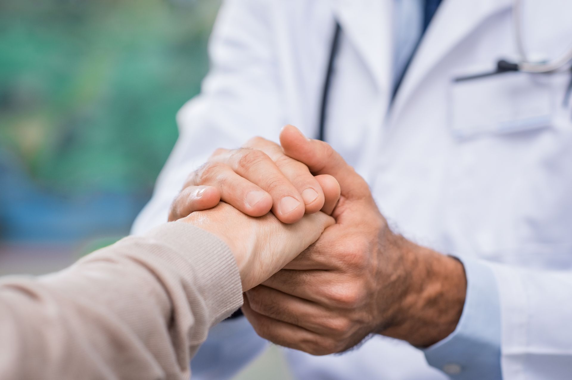 Doctor holding a patient’s hand in a comforting gesture in a clinic setting