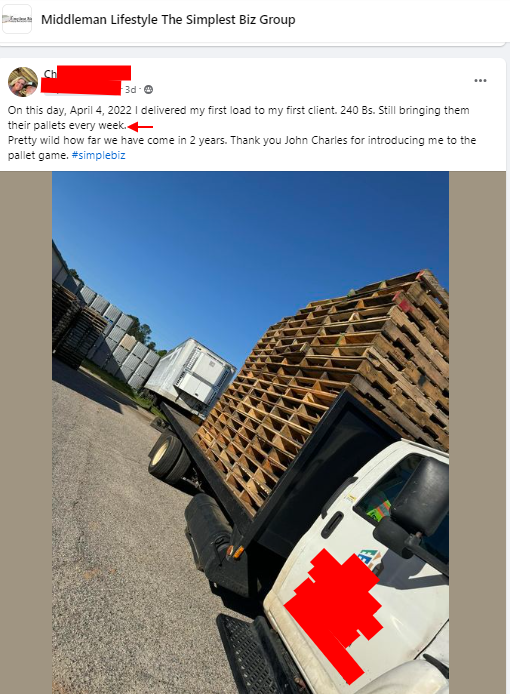 A white truck with a red cross on the side is carrying wooden pallets.