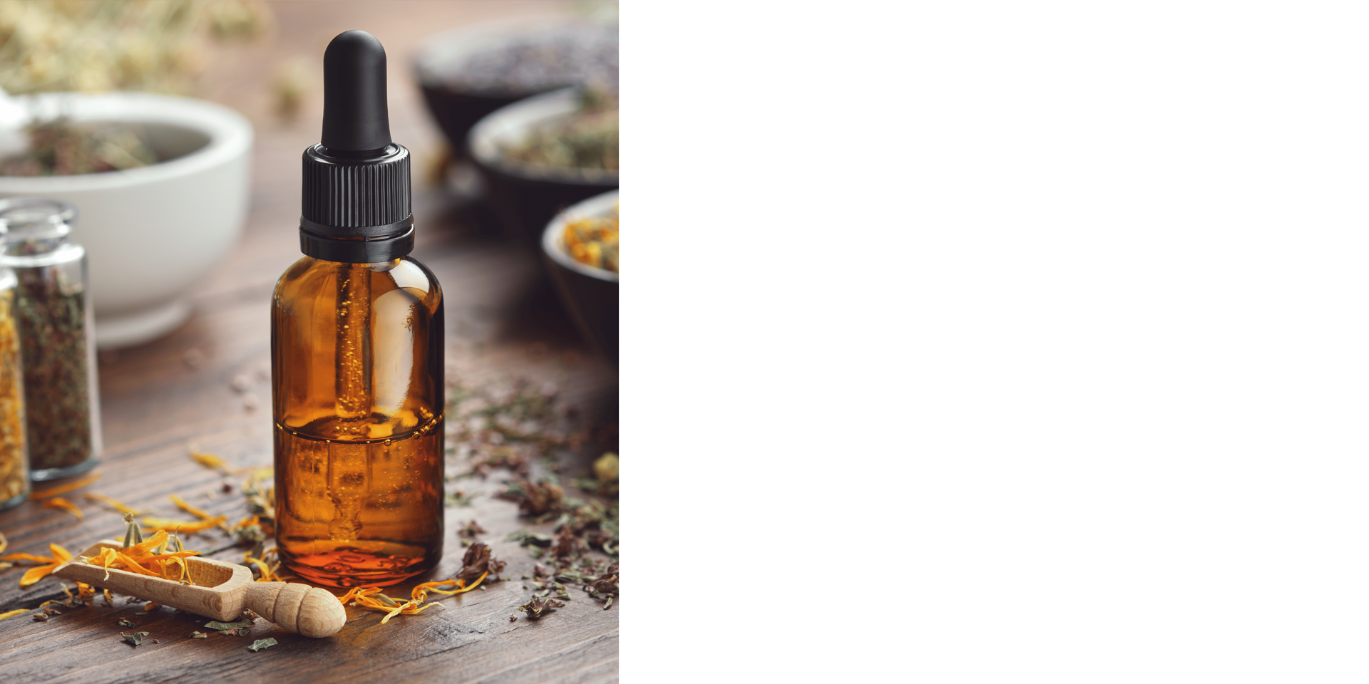 A bottle of essential oil with a dropper is sitting on a wooden table.
