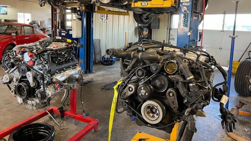 Two car engines on stands in a garage, one with red accents.