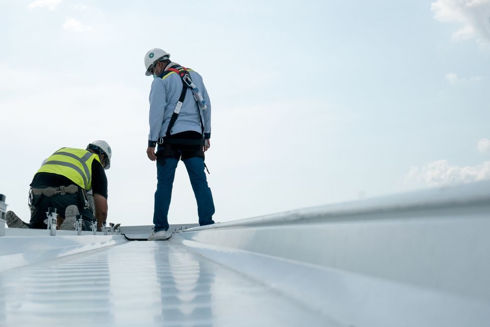 Two Construction Workers Are Working on a White Roof — Roof Restoration Masters In Gorokan, NSW