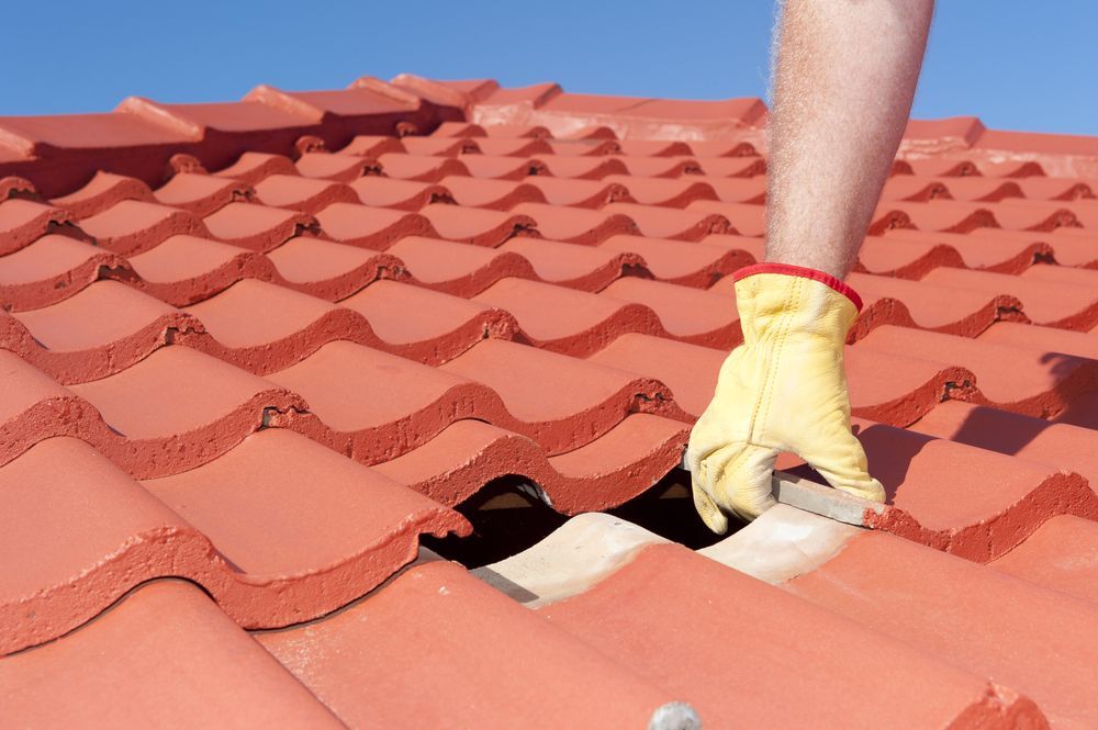 A Person Wearing Yellow Gloves is Working on a Tiled Roof — Roof Restoration Masters In Raymond Terrace, NSW