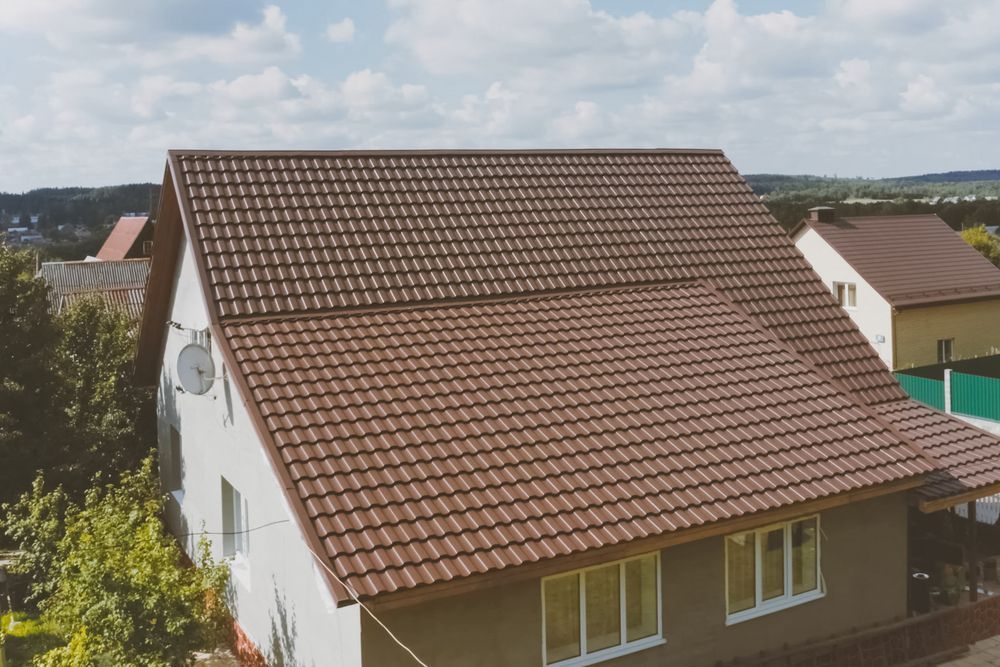 A Man Working on a Ladder on Top of a Tiled Roof — Roof Restoration Masters In Morisset, NSW