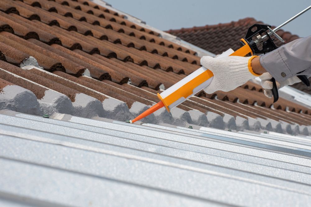 A Person is Applying Sealant to the Roof of a Building — Roof Restoration Masters In Cameron Park, NSW
