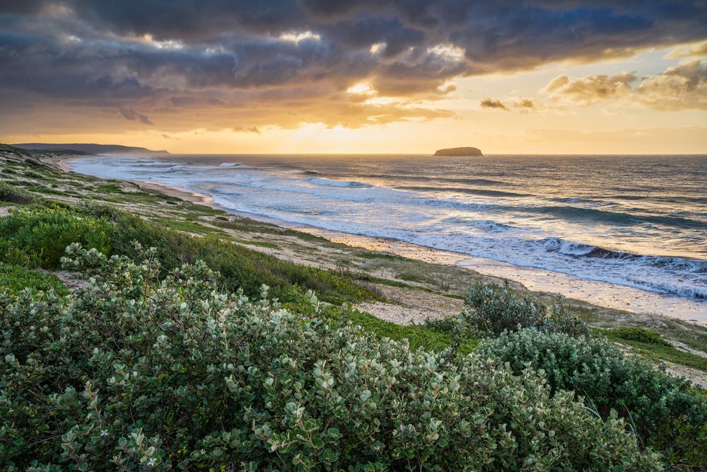 A Sunset Over a Beach With Waves Crashing on the Shore — Roof Restoration Masters In Budgewoi, NSW