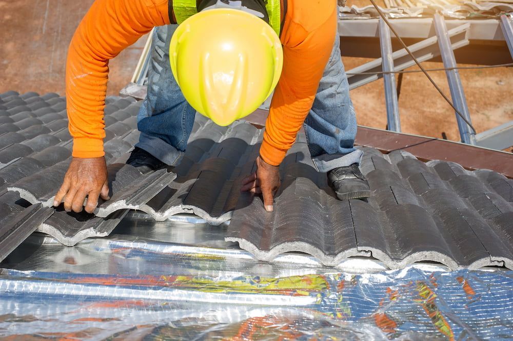A Man Wearing a Hard Hat is Working on a Roof — Roof Restoration Masters In Belmont, NSW