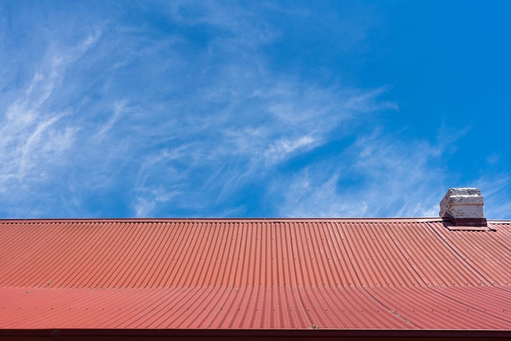 A Red Roof With a Chimney on Top of It — Roof Restoration Masters In New Lambton, NSW