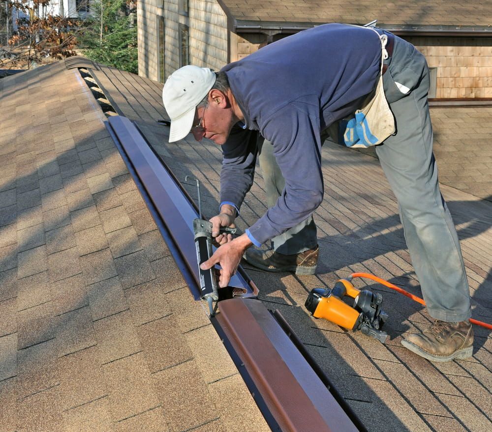A Man Wearing a White Hat is Applying Sealant on a Roof — Roof Restoration Masters In Newcastle, NSW