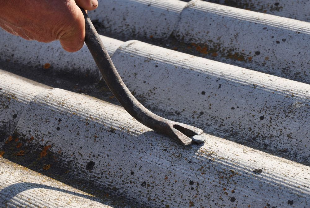 A Person is Using a Tool to Remove a Nail From a Roof — Roof Restoration Masters In Gosford, NSW