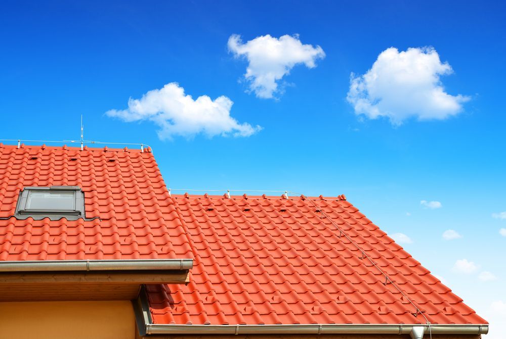 A Red Tiled Roof With a Skylight and a Blue Sky in the Background — Roof Restoration Masters In Cooranbong, NSW
