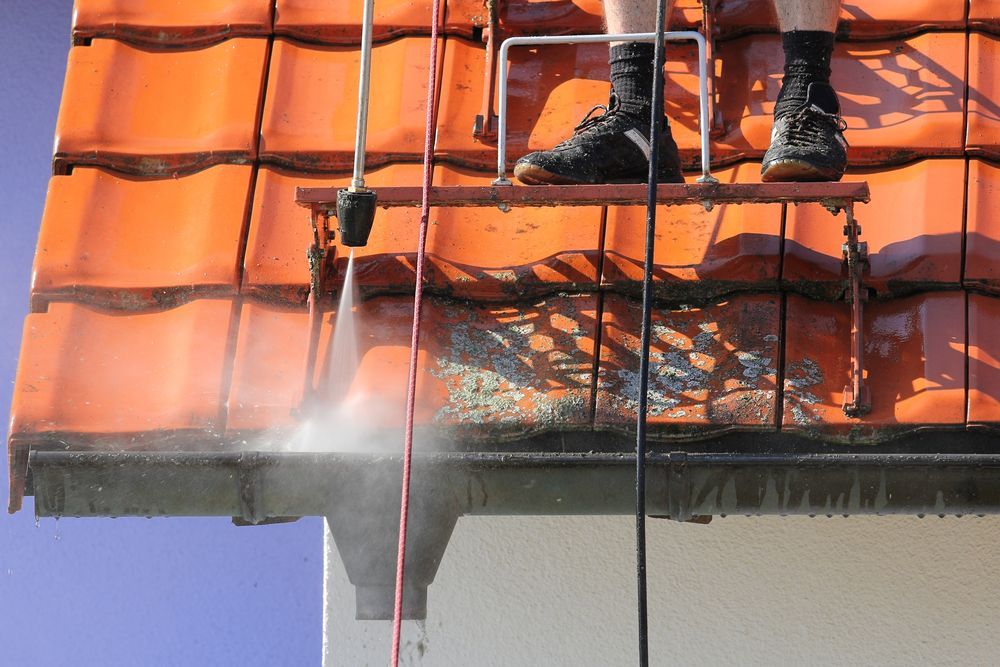 A Man is Using a High Pressure Washer — Roof Restoration Masters In Rutherford, NSW