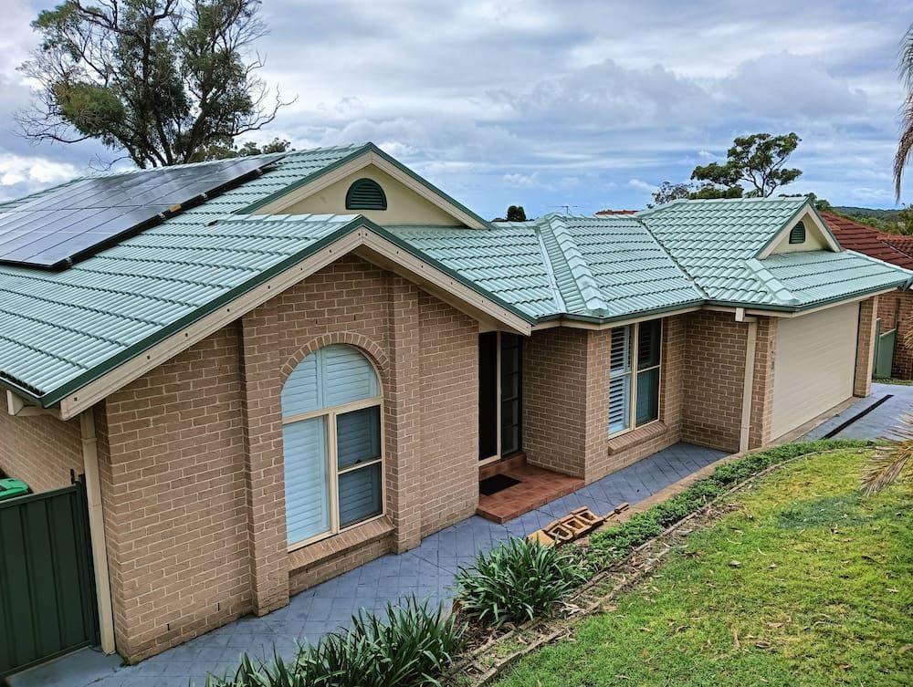 A Brick House With a Green Roof and Solar Panels on It — Roof Restoration Masters In Hamlyn Terrace, NSW