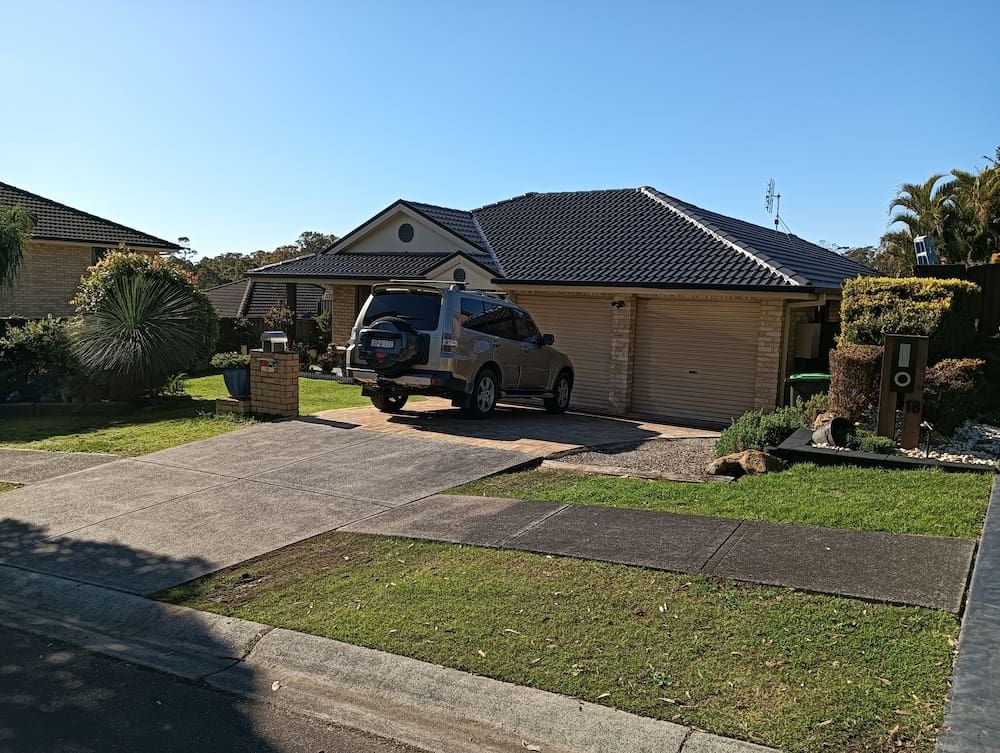 A Car is Parked in Front of a House on a Sunny Day — Roof Restoration Masters In Maryland, NSW
